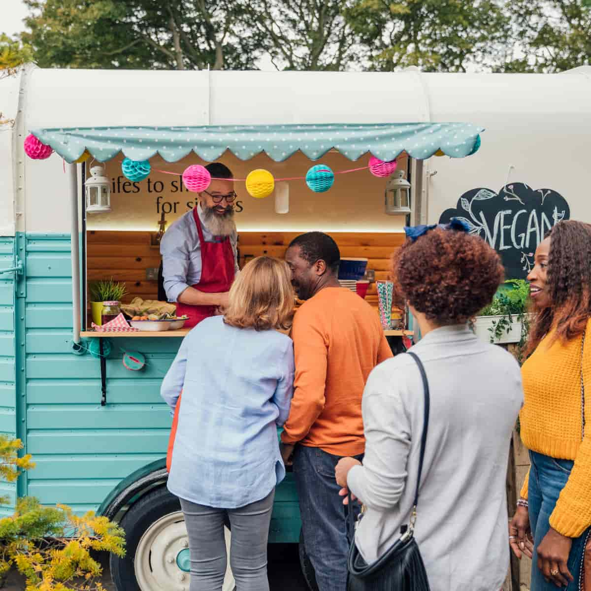 Line of people standing outside food truck.