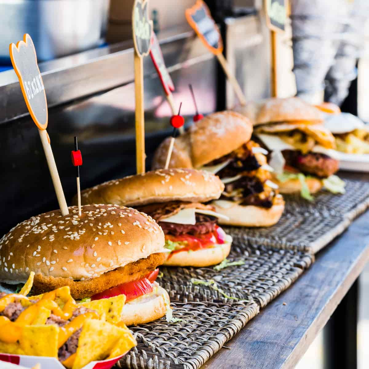 Four burgers sitting outside food truck.