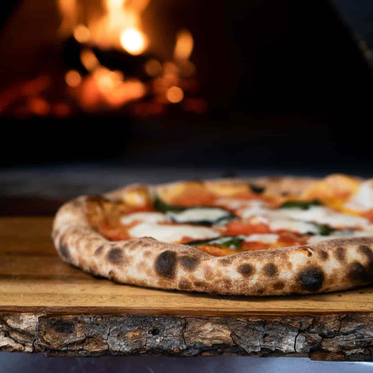 Pizza in front of wood burning oven.