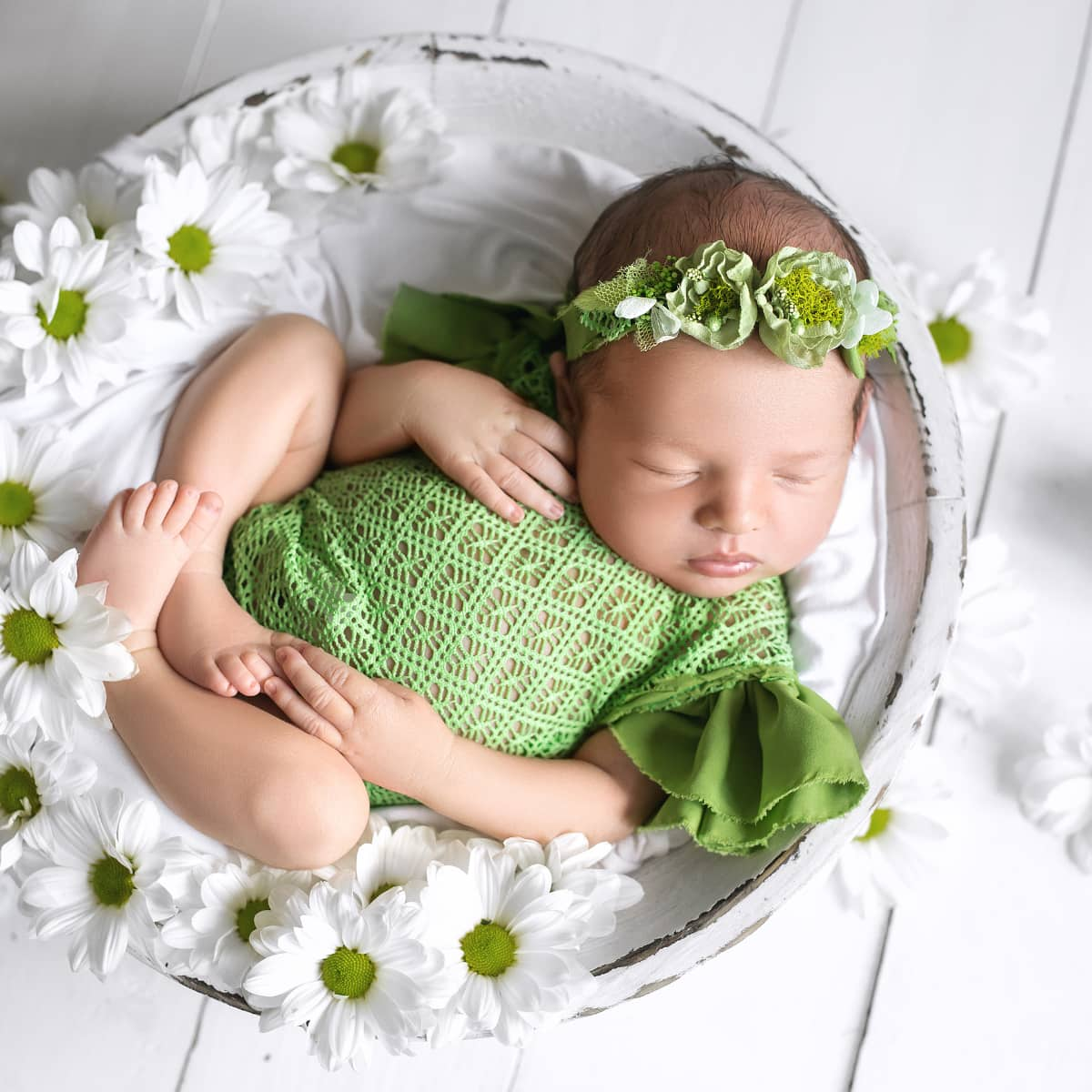 Newborn sleeping in container of flowers.