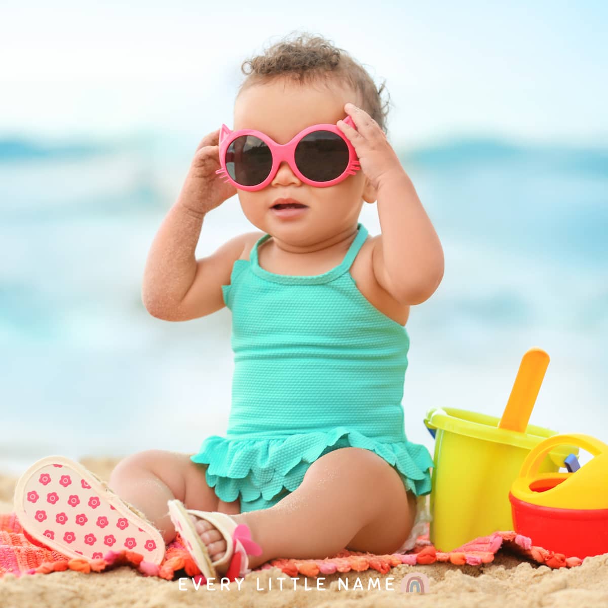 Baby girl wearing sunglasses at the beach.