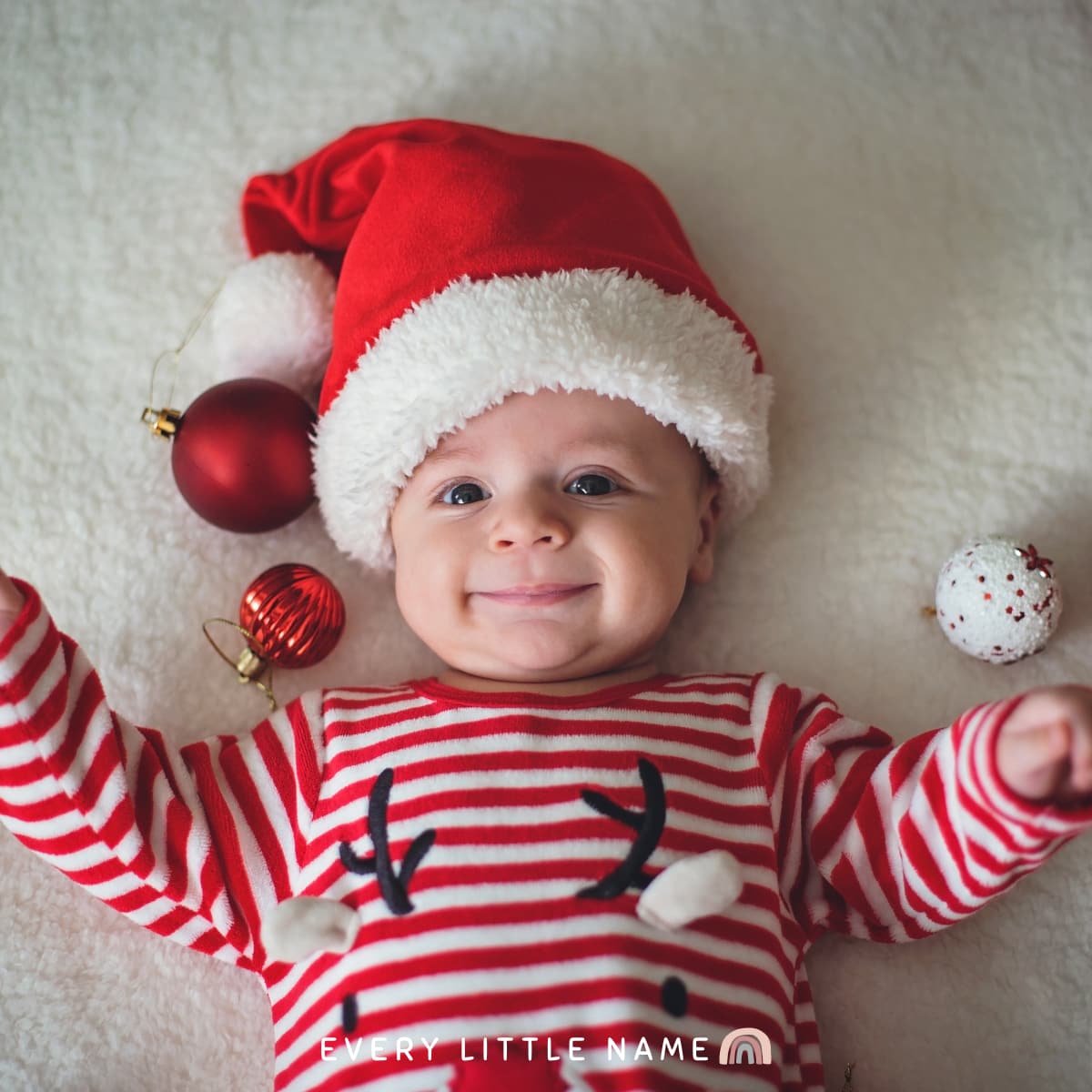Smiling baby wearing Christmas outfit.